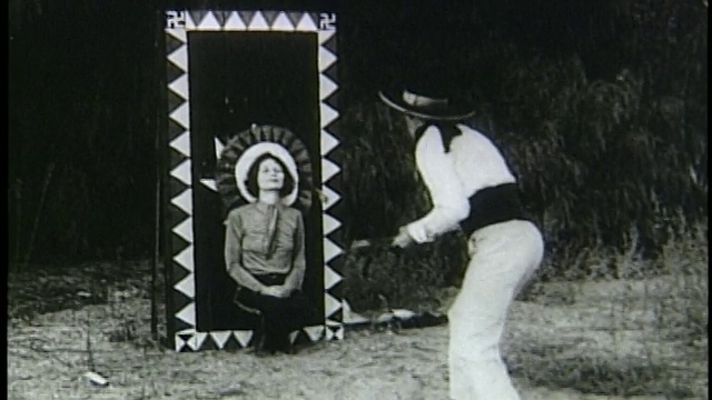 20世纪20年代/30年代的牛仔帽男子向跪在墙上的女子投掷刀子视频下载