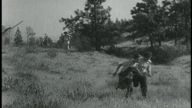 1934年，在俄勒冈州，手臂上带着方翼的潘人(汉克·法迪斯饰)在田野上奔跑，后面跟着狗/罗威纳视频素材