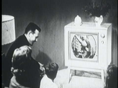 1956年高角度后视镜家庭坐在客厅看电视游行视频下载
