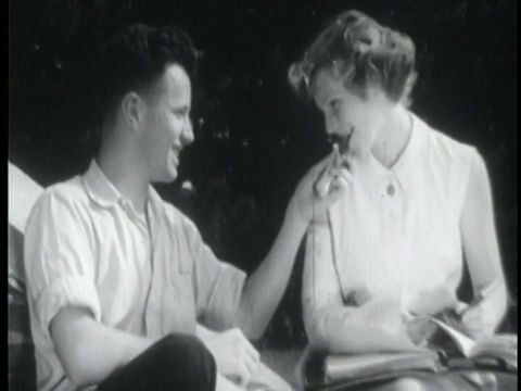 1955年一对青少年夫妇坐在户外分享糖果棒视频下载