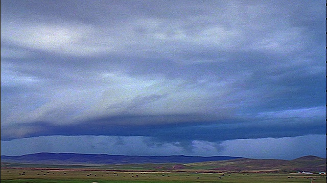 风暴云，雨+闪电平原上的动物放牧/山脉的背景视频素材