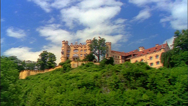 低角度变焦黄色的霍恩施万高城堡在绿色的山丘/德国巴伐利亚视频下载