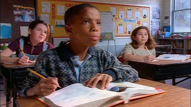 教室书桌前的学生/前排的黑人男孩举手回答视频素材