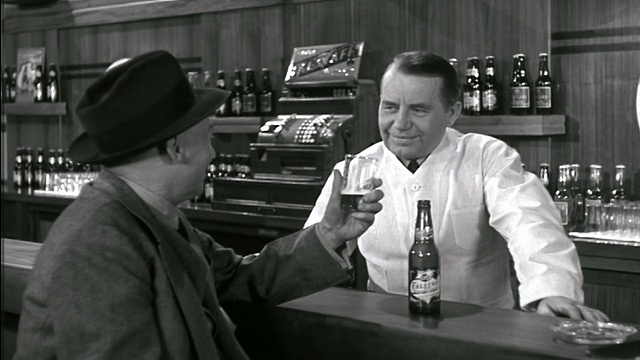 1942年，老男人坐在酒吧的高脚凳上喝啤酒+和酒保聊天/付给他工资+离开视频素材