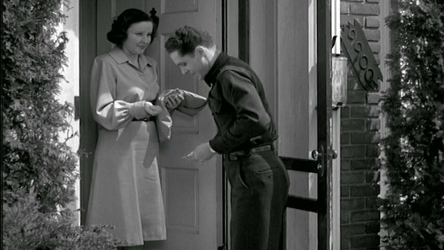 20世纪40年代，一名送货员在门口给一名女士递包裹，她给了他小费视频素材