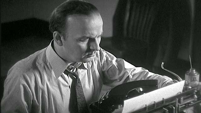 1936年，打领带的男人表情严肃地在打字机前打字视频素材