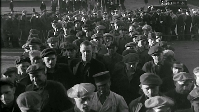 B/W 20世纪20年代/30年代戴着帽子的高角度男性蓝领工人走向摄像机进入工厂视频素材
