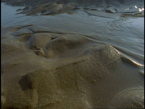 小溪从潮湿的沙堆上缓缓流过。视频素材