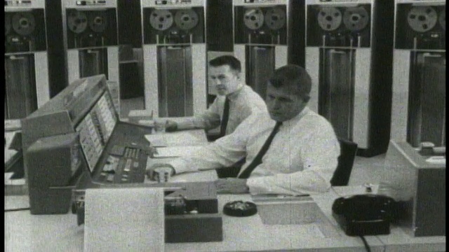 1965年，两个男人坐在电脑室里，拿着打印机视频下载