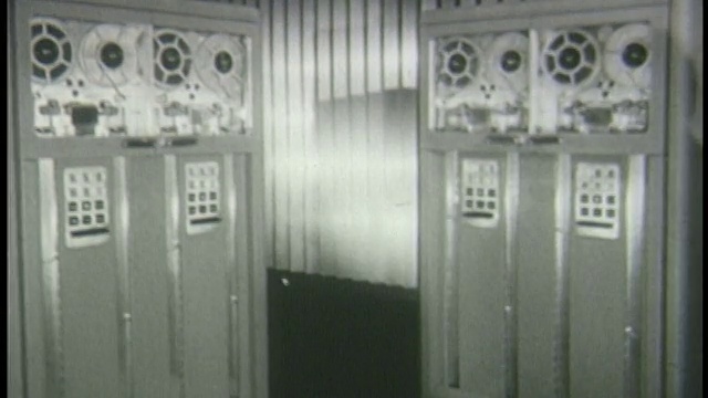 20世纪50年代的一名妇女拿着纺线盘走向巨大的电脑视频下载