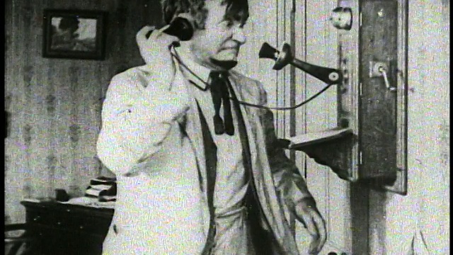 1921年，留胡子的男人(查理·默里)摇动发条墙电话/无声电影视频素材