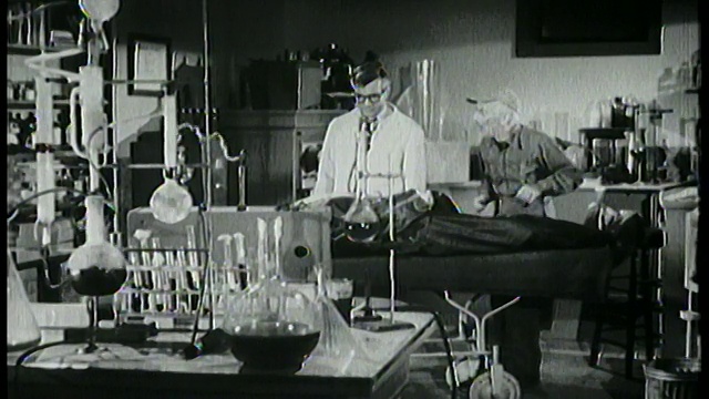 1958年，实验室里的科学家在桌子上检查尸体，年长的男人在看着视频下载