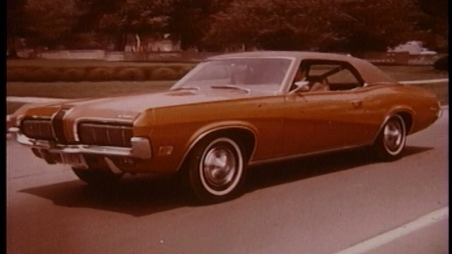1970年，追踪在郊区街道行驶的红色水星美洲豹视频下载