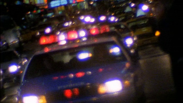一辆警灯闪烁的警车在夜晚驶向街道上的摄像头视频下载