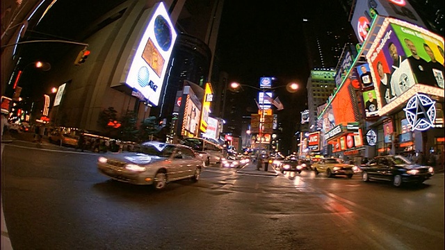 低角度轻微的鱼眼车辆经过摄像头在晚上的时代广场/纽约市视频下载