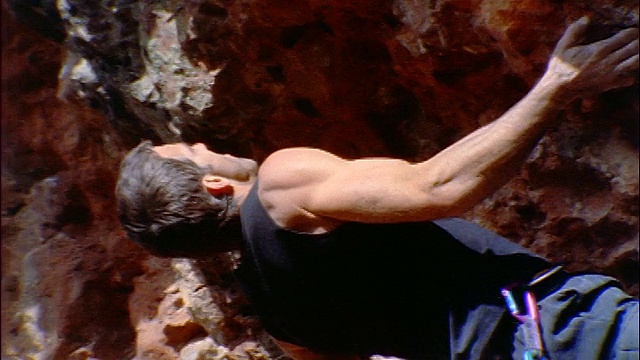 低角度男性攀岩者缓慢地攀登陡峭的岩石表面/新墨西哥视频素材