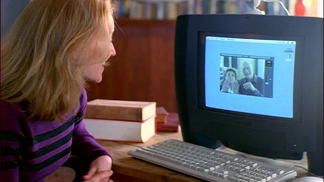 年轻的金发女子在公寓的电脑屏幕上与一对老年夫妇在电话会议/他们都招手视频下载