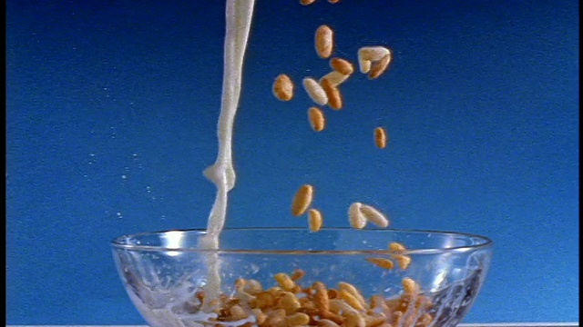 慢镜头近景CHROMA KEY麦片+牛奶倒入碗/蓝色背景视频下载