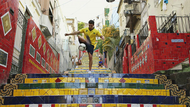 一名身穿巴西t恤的年轻人在Selaron台阶上用足球练习技巧视频购买