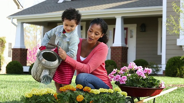 美国弗吉尼亚州里士满，DS WS女孩和母亲在屋前的花园里浇花视频下载