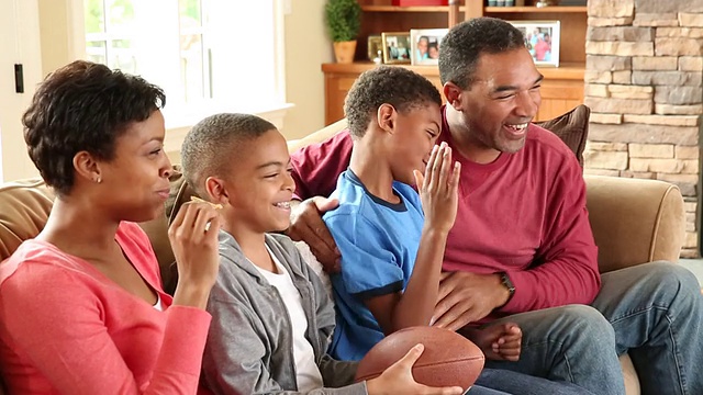 一个家庭和两个孩子在电视上看足球视频素材