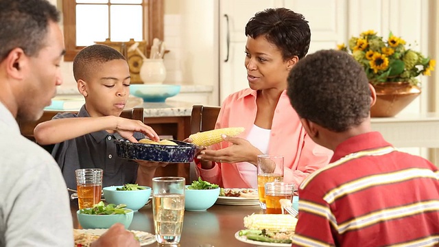 一个家庭和两个孩子在厨房吃晚饭视频素材