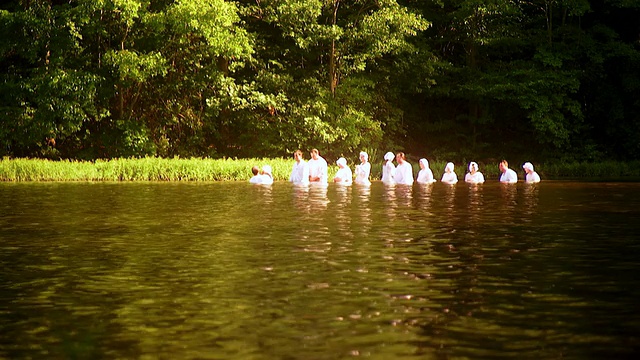 在洗礼仪式上，一排人站在湖中央，等待着他们被浸泡在水里。/费尔法克斯站，美国弗吉尼亚州视频下载