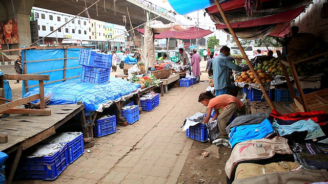 在孟加拉国达卡繁忙的街道上，人们走在卖水果和衣服的小贩中间视频下载