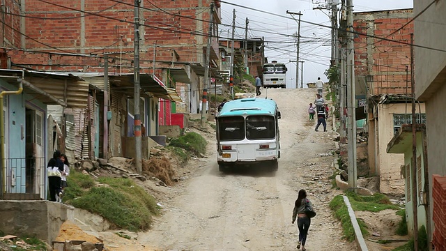 哥伦比亚波哥大Ciudad Bolivar贫民窟尘土飞扬的街道上的行人和车辆视频下载