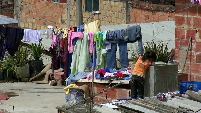 哥伦比亚波哥大的玻利瓦尔贫民窟，一个小女孩在晾衣服的晾线旁洗衣服视频下载