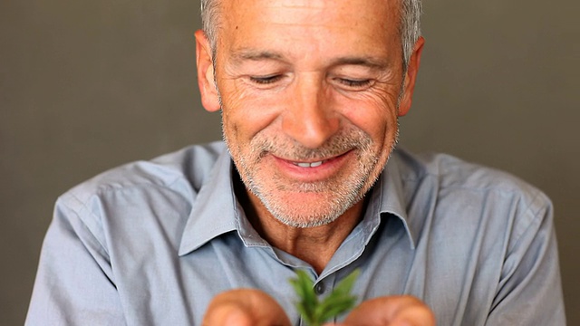老人抱着一株正在生长的绿色植物视频下载
