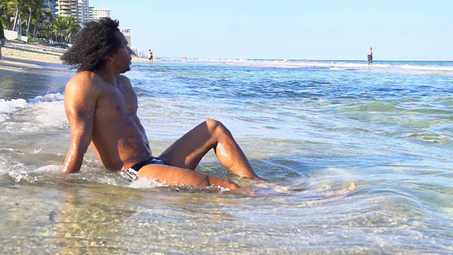 HD超级慢莫:性感男人坐在海滩上视频素材
