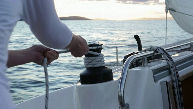 一名女子在游艇上用绞车缠绕绳索。视频素材