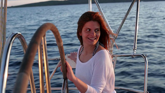快乐的女人在游艇尾部享受微风吹拂她的头发。视频素材