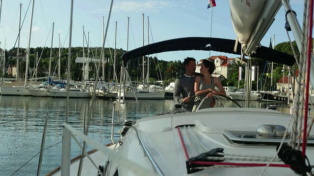 相爱的夫妇驾驶游艇离开码头。视频素材