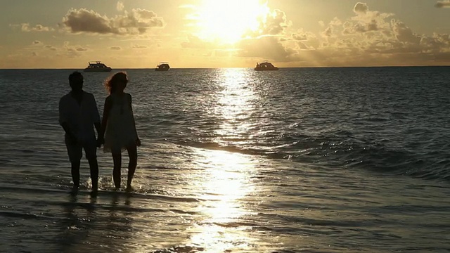 一对夫妇在日落时分的海滩上散步视频素材