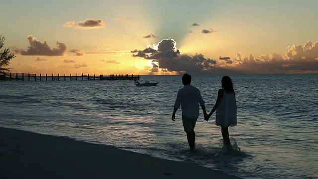 一对夫妇的剪影漫步在巴哈马日落的海滩上视频素材