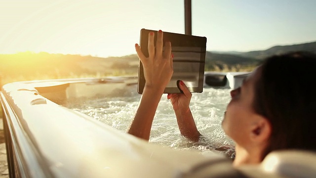 女人在漩涡按摩浴缸与数字平板电脑视频素材