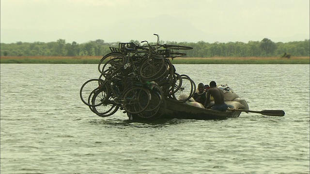 三个男人用划艇载着许多自行车横渡赞比西河。视频素材
