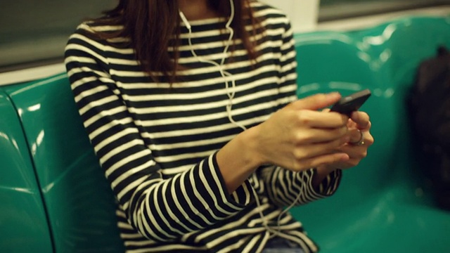 一个女人在地铁上听音乐。视频素材