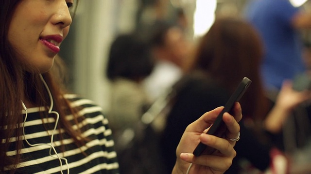 一名加州女子在火车上用手机听音乐。视频素材