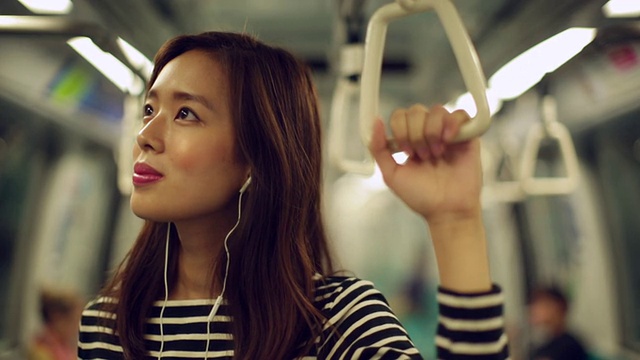 一名女子边听音乐边坐火车上下班。视频素材