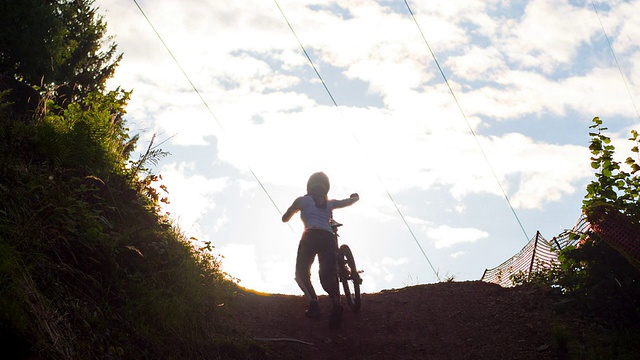 年轻的山地自行车手推着她的自行车上山视频素材