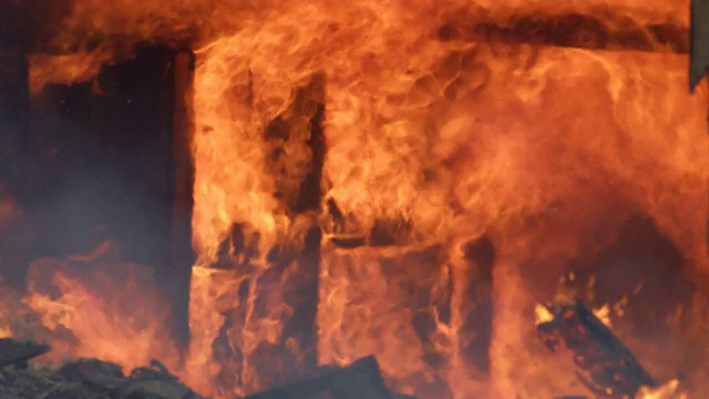 滚滚的火焰吞噬了一所燃烧的房子的内墙，碎片从上面落下视频素材
