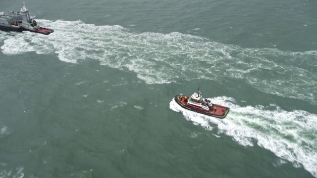在罗得岛小康普顿附近的海水中，一艘拖船和集装箱船。拍摄于2011年11月。视频下载