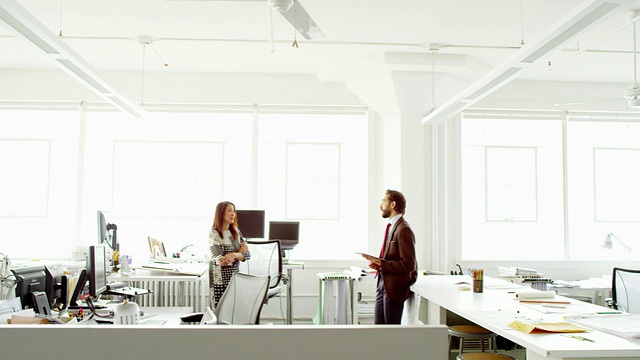 微软商人和女商人站在办公室的工作站讨论视频下载