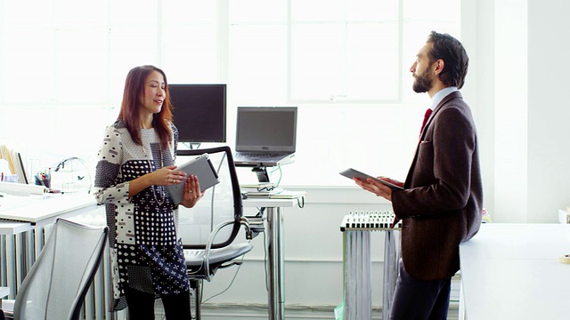 微软商人和女商人讨论项目的数字平板电脑在办公室工作站视频素材