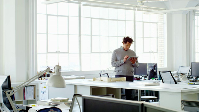 微软商人站在办公室里用数字平板电脑工作视频素材