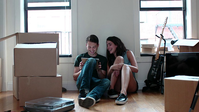小情侣在盒装公寓玩平板电脑视频素材
