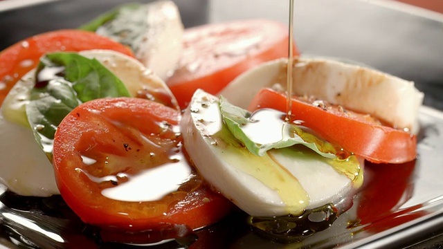 ECU马苏里拉番茄沙拉和罗勒在旋转沙拉盘上，并在沙拉上倒入初榨橄榄油视频下载